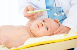 Female doctor checking newborn baby's temperature with thermometer